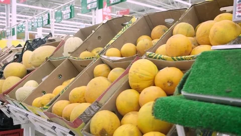 Young woman in dress selecting melon at the supermarket. A big pile of melons Stock Footage