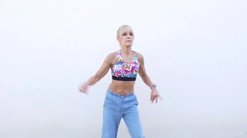 A young woman dressed casually is practicing dance moves near a wall, showing Stock Footage 316469537