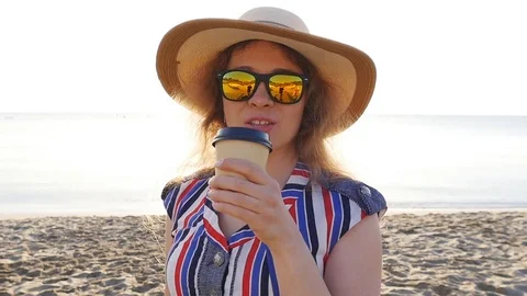 Young woman drinking coffee on the beach Stock Footage