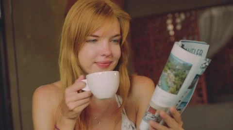 Young woman drinking coffee in rustic cafe, reading magazine Video stock 67849824