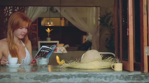 Young woman drinking coffee in rustic cafe, reading magazine Stock Footage 67849827
