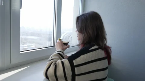 Young woman drinking a coffee while looking through the window Stock Footage 171923990