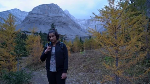 Young woman drinking from hydration backpack in mountainous scenery, Vidéo 120975654