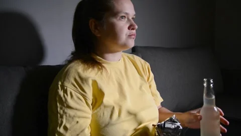 Young woman drinking kombucha while watching a movie in a dark room. Video stock 337000822