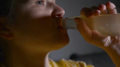 Young woman drinking kombucha while watching a movie in a dark room. 스톡 동영상 337069376