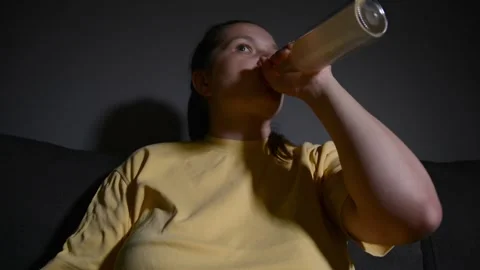 Young woman drinking kombucha while watching a movie in a dark room. 库存影片 337069596