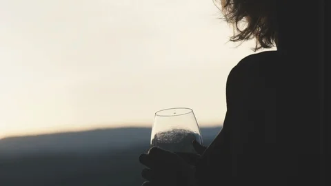 Young woman drinking red wine from a glass and watching on sunset Stock Footage