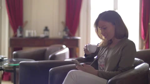 Young woman drinking tea while using her phone Stock Footage 64548210