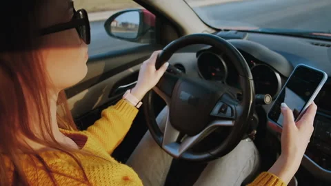 Young woman driver using mobile phone while driving car in motion, slow motion Stock Footage 231803148