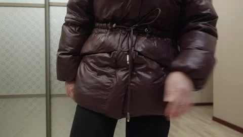 Young woman dusting off jacket with hand indoors, clothing care 動画素材 326026239