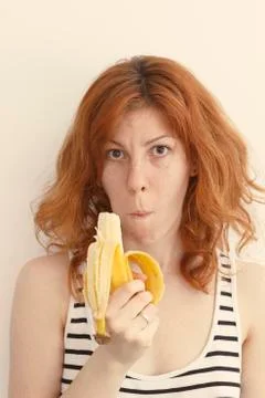 Young woman eating a banana, making a funny face Stock Photos