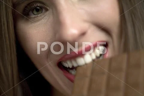 Young woman eating bar of chocolate, portrait, close-up Stock Photos