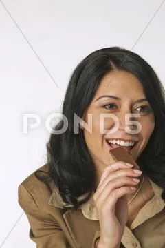 Young woman eating chocolate bar, smiling, portrait Stock Photos