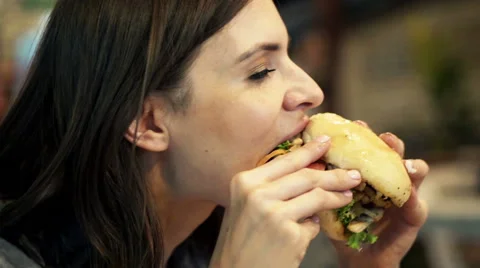 Young woman eating fast food, hamburger in cafe HD Stock Footage