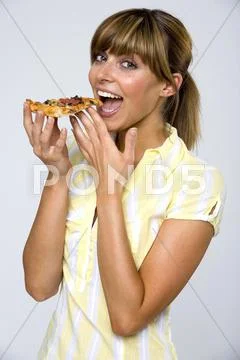 Young woman eating slice of pizza, smiling Stock Photos