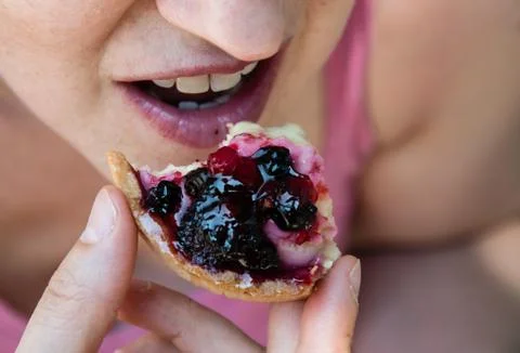 A young woman eats a cake with fruit Stock Photos