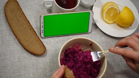 A young woman eats a salad of beets with garlic and looks into the green scre Stock Footage 102297576