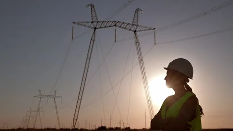 Young woman electrical engineer adjusts her white safety helmet on her head and Stockbeeldmateriaal 208741815