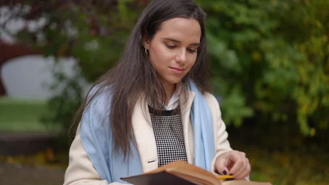 A Young Woman Engaged in Reading While Surrounded by Nature and Beautiful Autumn Stock Footage 297393241
