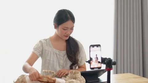 Young woman engaging with smartphone while recording video tutorial on fash.. Vídeos de archivo 332976590