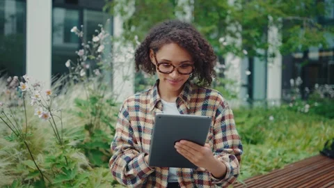Young woman engaging with a tablet while sitting in a serene and beautiful Stock Footage 313268582