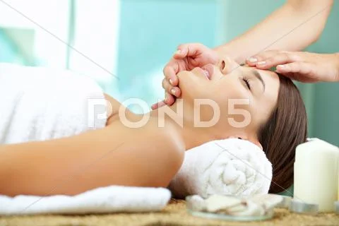 Young woman enjoying facial at spa salon Stock Photos