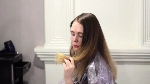 Young woman is examining her split ends while waiting for the hairdresser Stock Footage 192960291