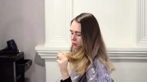 Young woman is examining her split ends while waiting for the hairdresser Stock Footage 192960293