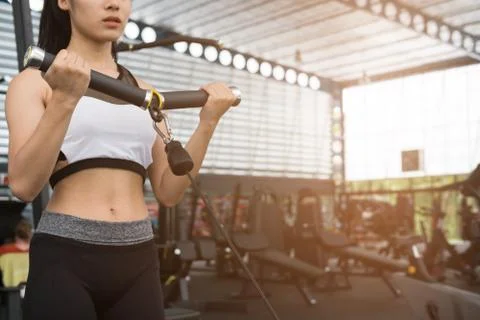 Young woman execute exercise with machine in fitness center. female athlete p Stock Photos