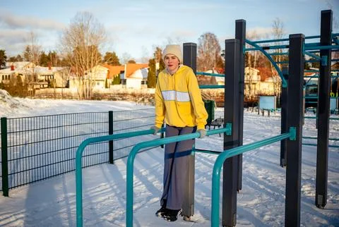 Young woman exercising on outdoor parallel bars in winter. 스톡 사진