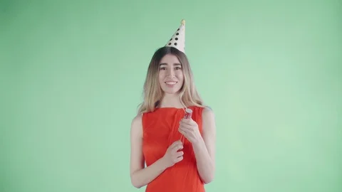 Young woman exploding confetti cracker on a green background. Stock Footage 108619694