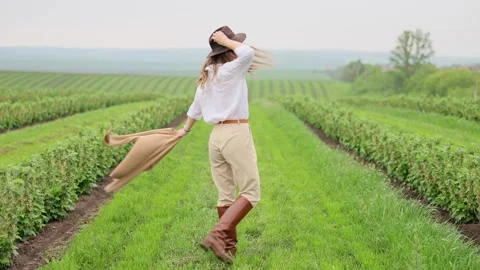 Young woman exploring fields wearing hat and boots Stock Footage 335779125