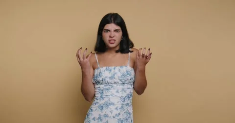 Young woman expresses frustration while standing in front of a plain backgr.. Vídeo Stock 326793003