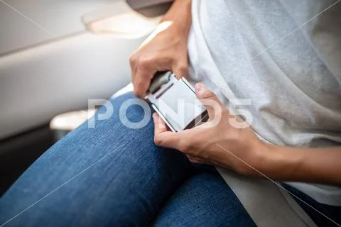 Young woman fastening her seat-belt during a flight on a commercial aircraft Stock Photos