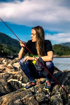 Young woman is fishing in Norway in the fjord. Stock Photos