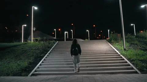 Young woman gently climbs the high stairs in the night park Vidéo 144851353