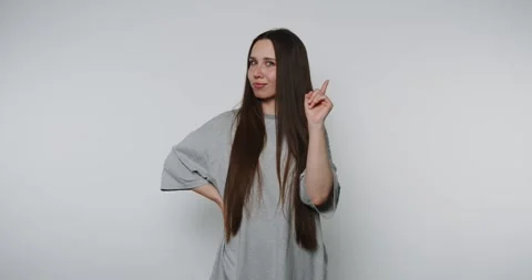 Young woman gestures playfully while looking thoughtful against a plain bac.. Stock Footage 313951798