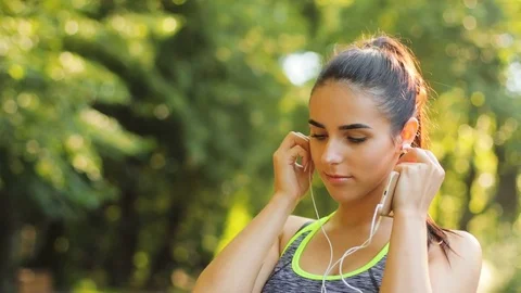 Young woman getting ready to the running in the park using earphone for Stock Footage