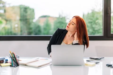 Young woman getting up while working in the office or at home. Stock Photos