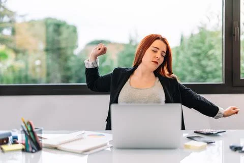 Young woman getting up while working in the office or at home. Stock Photos