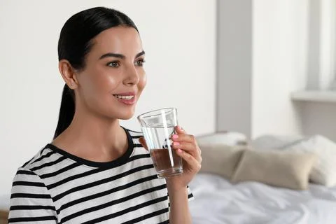 Young woman with glass of water indoors, space for text. Refreshing drink Stock Photos
