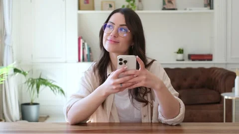 Young woman with glasses smiling while texting on her smartphone Stock Footage 335588253