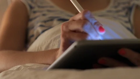 Young woman in glasses is using tablet pc with pen at night Stock Footage 99451285