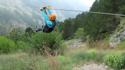 Young woman is going down the zip line among mountains and sea in clouds Stock Footage 122575278