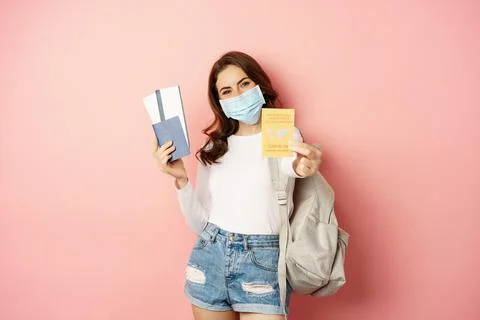 Young woman going on trip, wearing medical mask, showing covid certificate Stock Photos