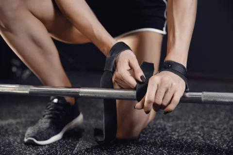 Young woman hands put straps on her wrists for barbell insurance gym. Workout Stock Photos