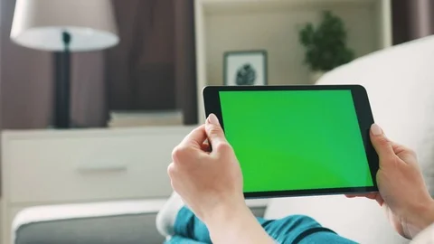 Young woman hands using tablet with green screen, lieng on sofa at home. View Video stock 75737486