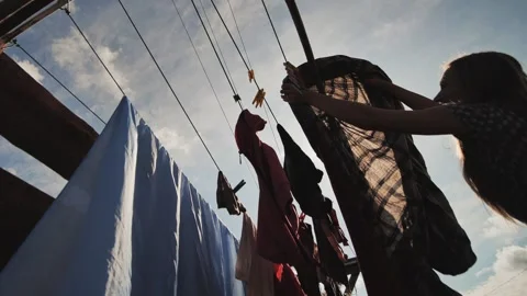 A young woman hangs clothes for drying on a summer day. Stock Footage
