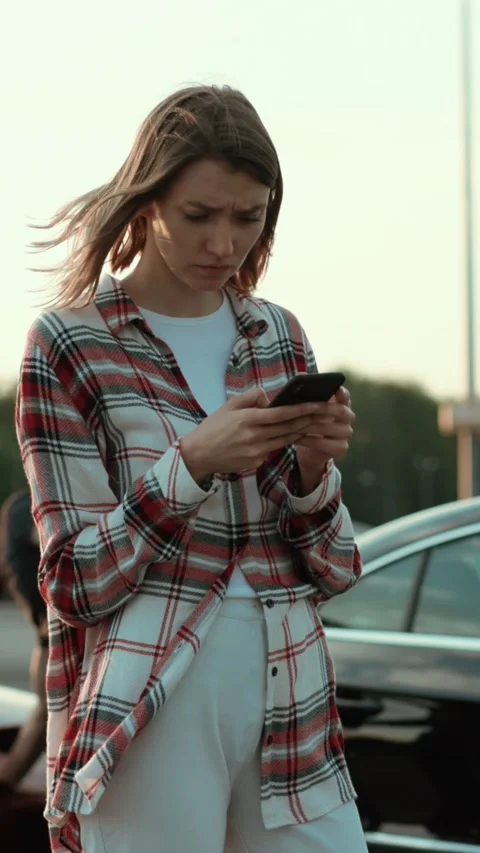 A Young Woman Happily Using Her Smartphone While Relaxing in a Casual Outdoor Stock Footage 313774747