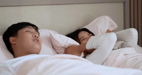 Young Woman has problem form her husband snoring while sleeping on bed. Stock Footage 198998561